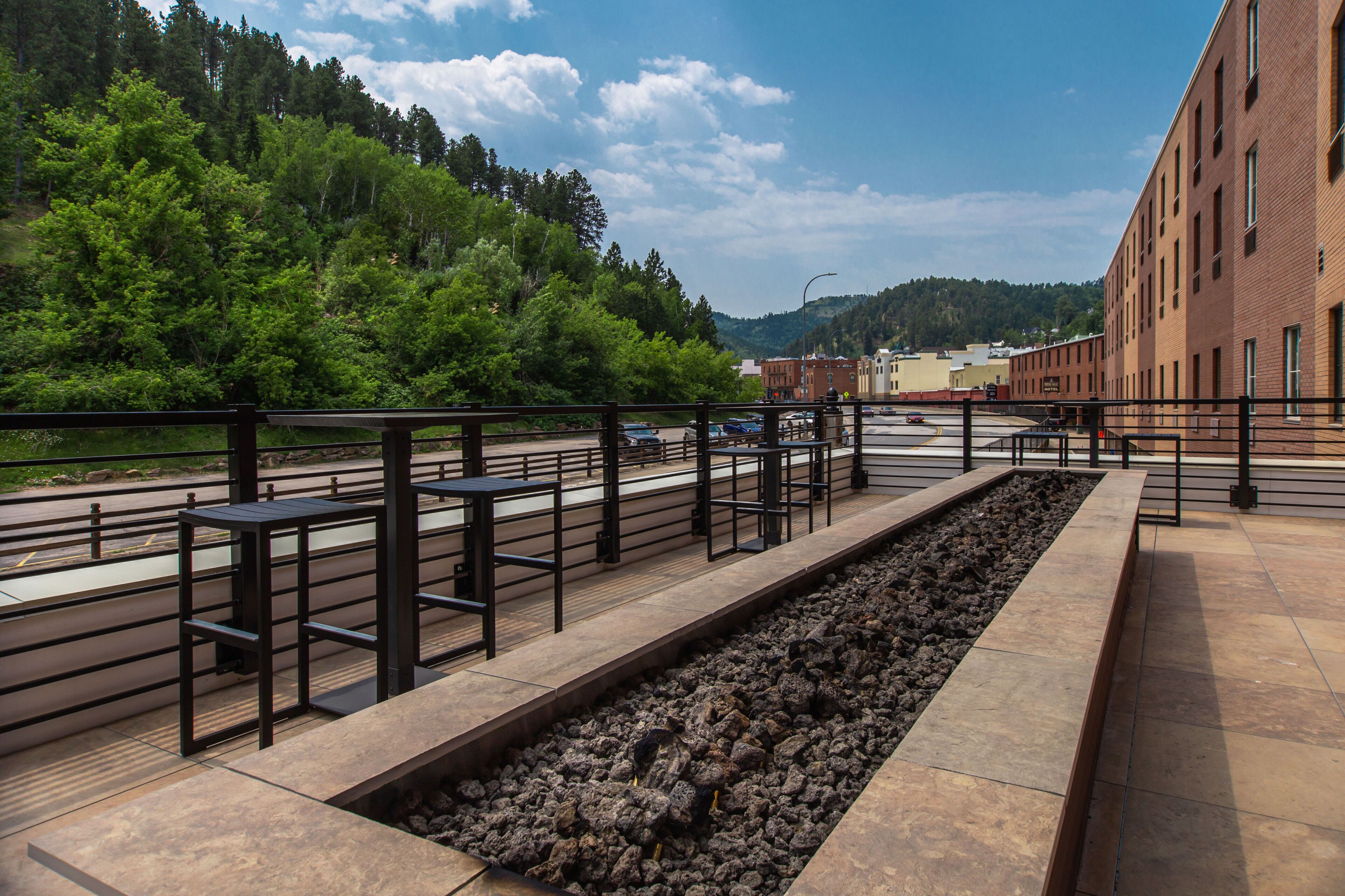 A riverside walkway with benches and a brick building in the background.