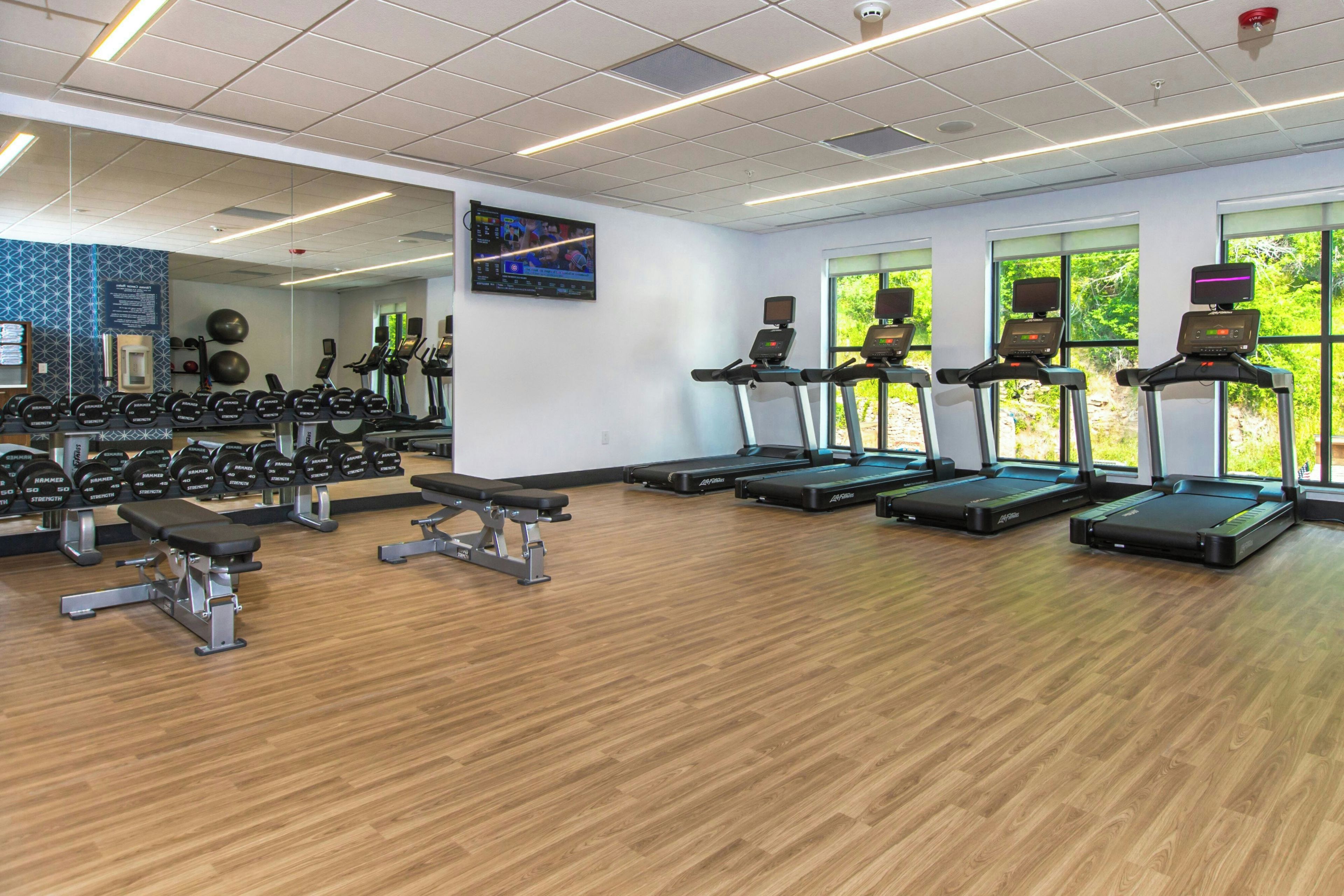 Een sportschool met loopbanden, gewichten en halterplaten.