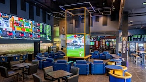 A sports bar with multiple screens, blue seating, and a large TV displaying a baseball game.
