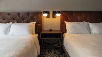 Una habitación de hotel con dos camas, una mesita de noche y dos lámparas fijadas a la pared.