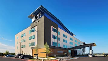 Un hotel moderno con techo plano, múltiples ventanales y un acceso cubierto.