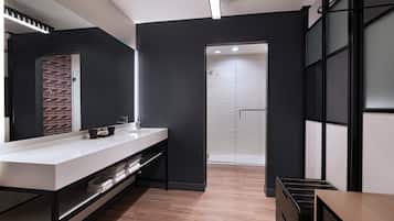 Un baño moderno con un espejo grande, una encimera blanca y un mueble de tocador negro.