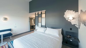 Ein modernes Hotelzimmer mit einem großen Bett, einem Schreibtisch und einem Spiegel.