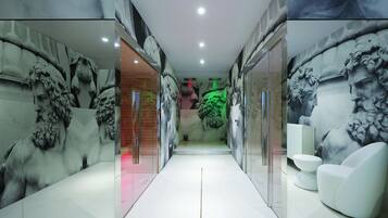 Un baño moderno con paredes de mármol, cabina de ducha de vidrio y un inodoro blanco.