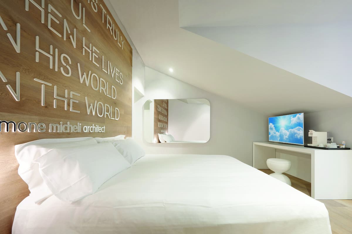 Un dormitorio moderno con una cama grande, un televisor y una pared con citas motivacionales.
