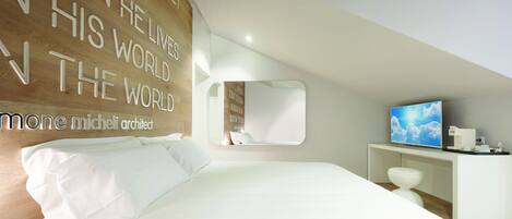 A modern bedroom with a large bed, a TV, and a wall with motivational quotes.