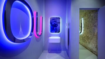 Ein modernes Badezimmer mit einer runden Leuchte, einem kleinen Waschbecken und einer Steinwand.