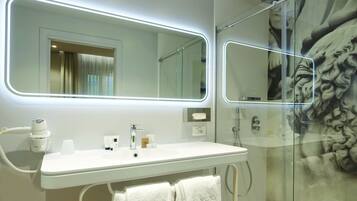 Ein modernes Badezimmer mit weißem Waschtisch, einem großen Spiegel und einer Duschkabine aus Glas.