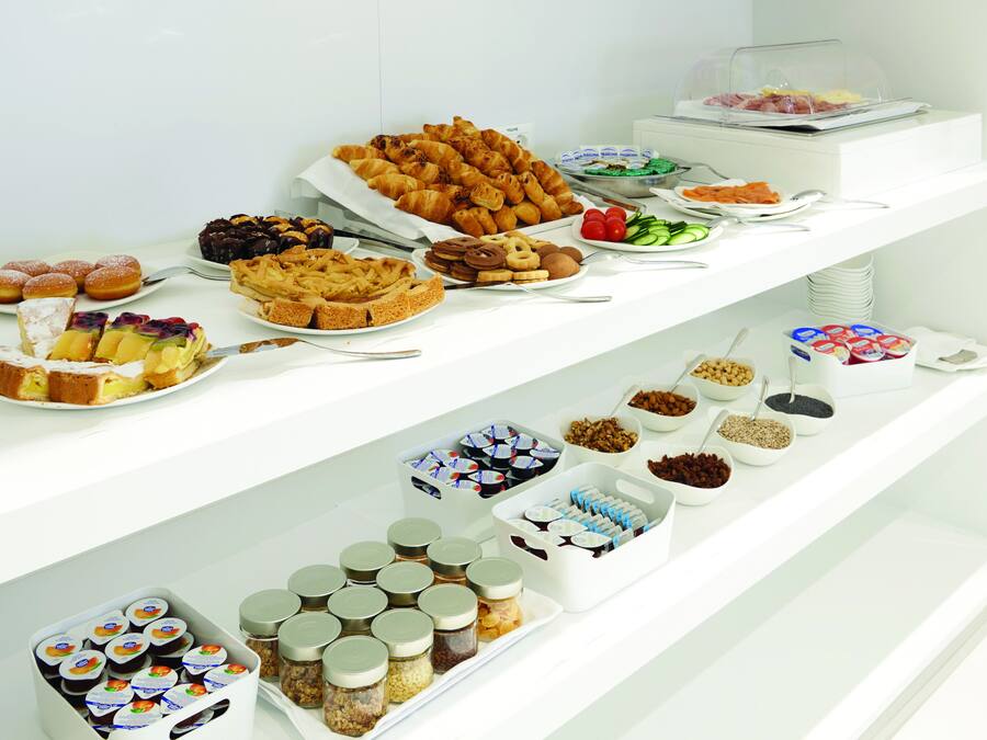 A buffet with various food items including pastries, fruits, and condiments.