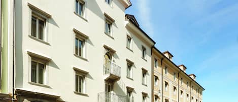 A multi-story hotel with a row of balconies, a clear sky, and a street with a bus lane.