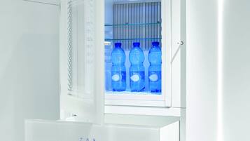 A white refrigerator with a digital keypad and a glass door. Inside, there are blue water bottles.