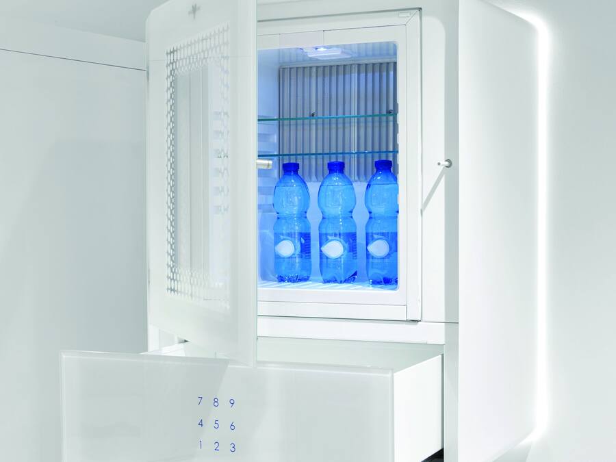 A white refrigerator with a digital keypad and a glass door. Inside, there are blue water bottles.