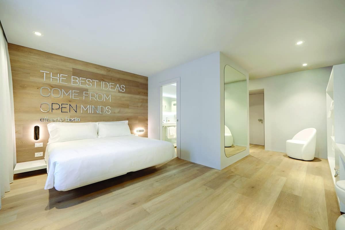 Un dormitorio moderno con una cama grande, un espejo y una pared con texto motivacional.