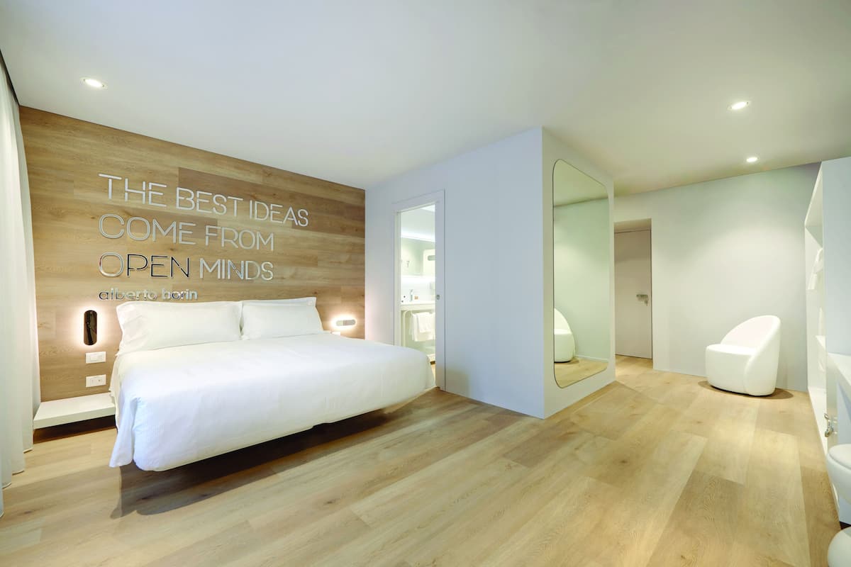 Un dormitorio moderno con una cama grande, un panel de madera decorativo y una cita motivacional.
