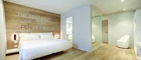 A modern bedroom with a large bed, a wooden accent wall, and a motivational quote.