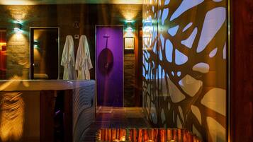 Bathroom features a large mirror with integrated lighting, a vanity with a countertop, and a decorative wall panel.