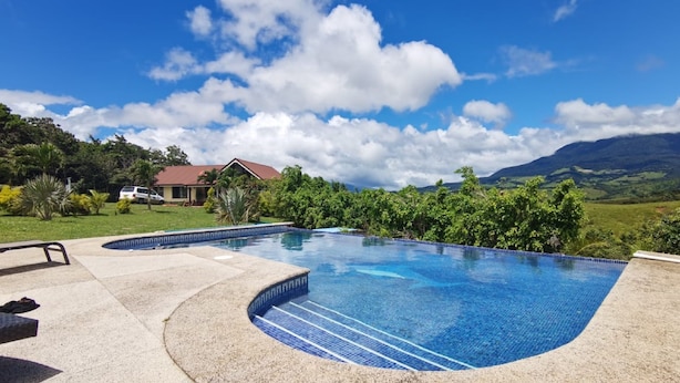 A swimming pool with a curved edge, surrounded by a concrete deck. - Vistas del Tenorio (Tierras Morenas)