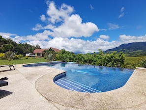 Une piscine à bordures courbes, entourée d’une terrasse en béton.
