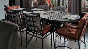 A dining area with a round table and chairs, large windows with curtains, and a clock on the wall. - Vistas del Tenorio (Tierras Morenas)
