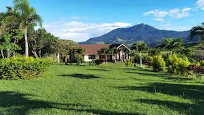 A house with a red roof surrounded by lush greenery and a mountain in the background. - Vistas del Tenorio (Tierras Morenas)