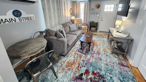 A compact living space with a sofa, coffee table, and a small dining table. - Ivy's Cottage- Renovated, In Town. Great Location. (Chincoteague)