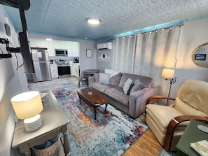 A compact living space with a kitchenette, a sofa, a coffee table, and a dining table.