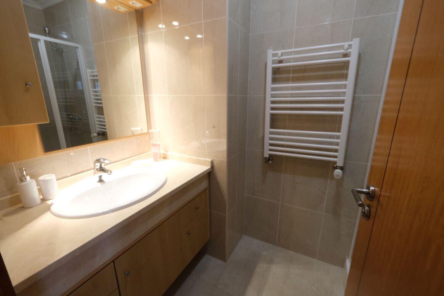 Un baño moderno con lavamanos, espejo y toallero.