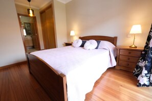 A neatly arranged bedroom with a wooden bed, two bedside lamps, a mirror, and a wooden nightstand.