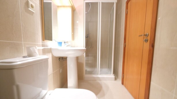Une petite salle de bain avec des toilettes, un lavabo et une douche.