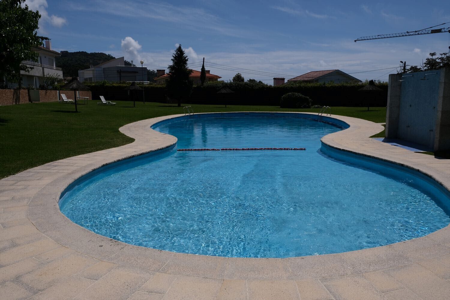 A swimming pool with a curved edge, surrounded by a paved deck.