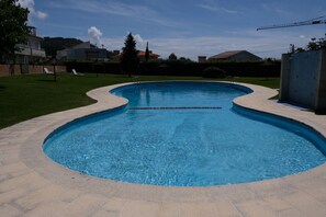 A swimming pool with a curved edge, surrounded by a paved deck.