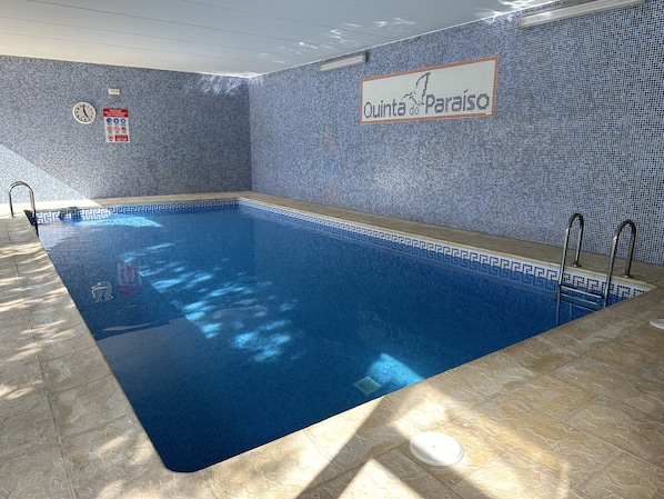 An indoor swimming pool with a tiled wall and a sign reading "Quinta do Paraiso".