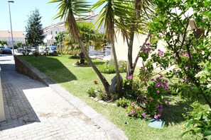 A paved pathway alongside a well-maintained garden with palm trees and flowering plants. - Holiday rental house  pool tennis ESPOSENDE PR991 (Esposende)