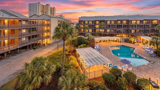 Un hotel con varias plantas, piscina y zonas de estar al aire libre.