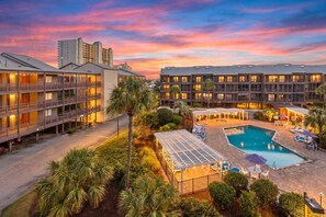 A hotel with multiple floors, a swimming pool, and outdoor seating areas.