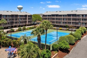 A hotel with a tennis court, palm trees, and a water tower. - Tilghman Beach & Racquet Club 346 - location and amenities galore! (North Myrtle Beach)