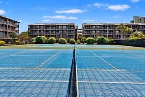 Un terrain de sport avec un filet au centre, entouré d’immeubles à plusieurs étages dotés de balcons.