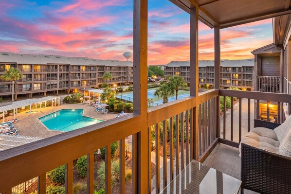 A hotel with a pool, outdoor seating, and a view of other hotel buildings.