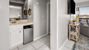 Una cocina moderna con lavavajillas, un refrigerador pequeño y un aparador de madera con televisor.