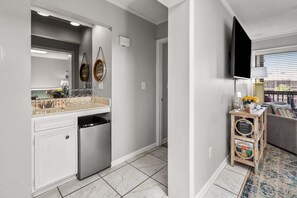 Una cucina moderna con lavastoviglie, un piccolo frigorifero e un mobiletto in legno con televisore.