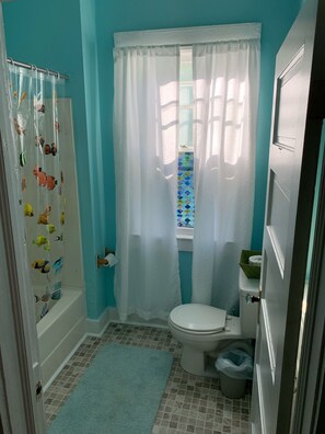 Bañera con ducha, toallas, jabón, papel higiénico