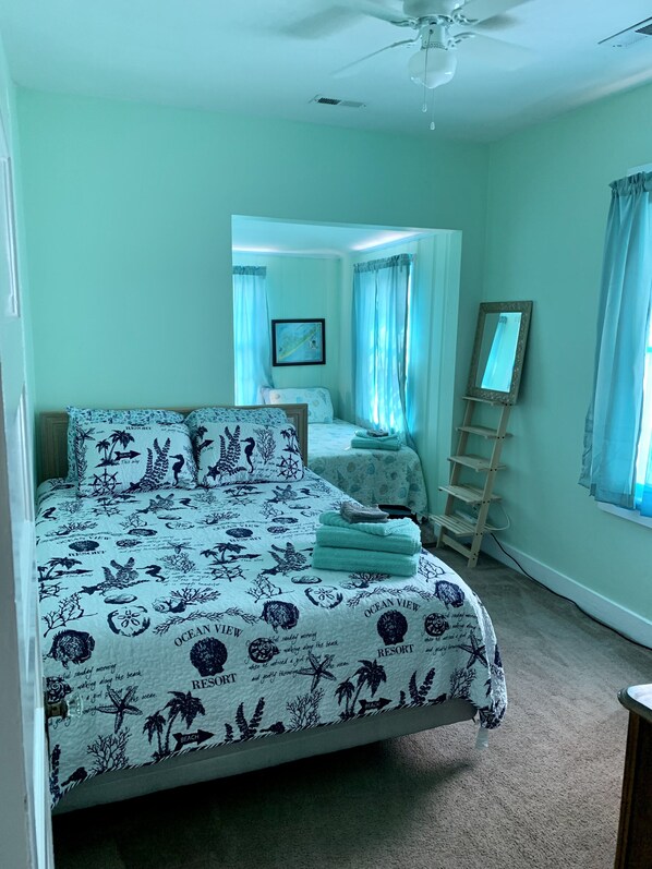 Une chambre à coucher avec un lit, une table de chevet, un miroir et une fenêtre avec des rideaux.