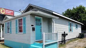 A single-story house with a front porch, a mailbox, and a trash bin.