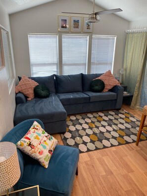 Relax in this inviting living room with a large sofa, ceiling fan, and cozy rug.