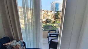 Un balcon donnant sur des immeubles et un petit espace extérieur aménagé avec des sièges.