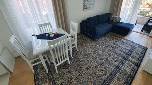 Un salon avec une table blanche, un canapé bleu et un tapis à motifs.