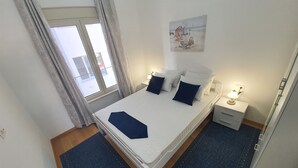 Une chambre à coucher avec un lit, des tables de chevet, une lampe, un tableau au mur et une fenêtre avec des rideaux.