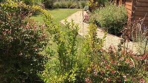 Eine Holzhütte mit der Nummer 33, umgeben von einem Garten mit verschiedenen Pflanzen und einer Rasenfläche.