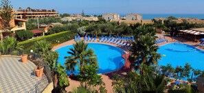 A resort with two large swimming pools surrounded by palm trees and lounge chairs. - Dolcestate (Campofelice di Roccella)