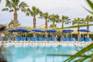 A poolside area with blue umbrellas and lounge chairs. - Dolcestate (Campofelice di Roccella)